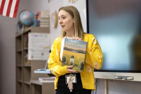 Student teacher holding up a book in a classroom